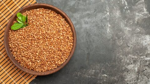overhead view buckwheat groats with green brown bowl brown tray gray background